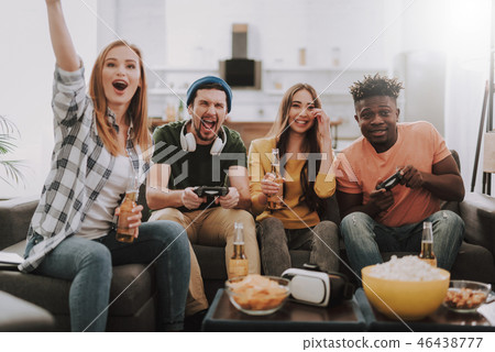 Cheerful friends playing video games and enjoying drinks at home 46438777