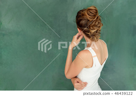 Young beautiful brunette with stylish hair smiles Think pose on a green background Young beautiful brunette with stylish hair smiles Think pose on a green background 46439122