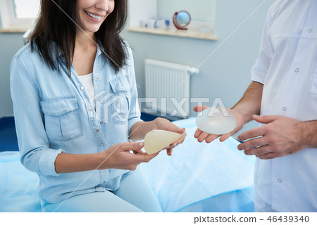 Smiling woman looking on breast implant in hospital Smiling woman looking on breast implant in hospital 46439340