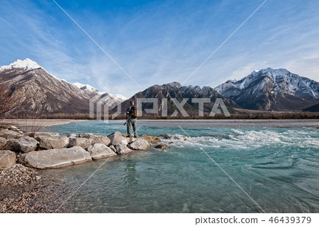 Man hiker on shore of river looking the mountains 46439379