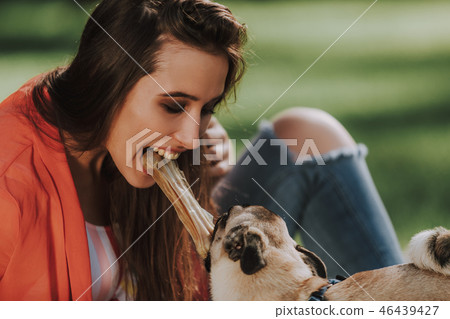 Happy owner is playing with her dog and biting toy bone Happy owner is playing with her dog and biting toy bone 46439427