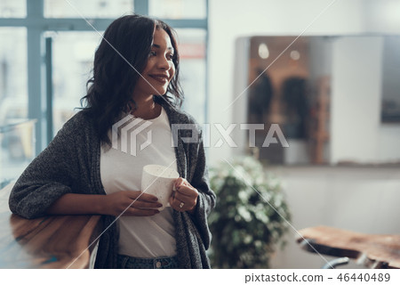 Waist up of smiling lady standing with white cup in her hands Waist up of smiling lady standing with white cup in her hands 46440489