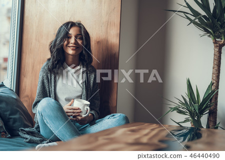 Pretty lady sitting next to the window with cup and smiling 46440490