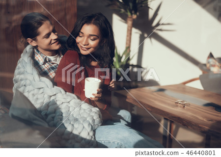 Romantic couple wrapping themselves into warm blanket and smiling Romantic couple wrapping themselves into warm blanket and smiling 46440801