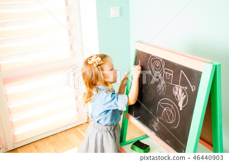 Pretty little girl drawing with chalk on a blackboard Pretty little girl drawing with chalk on a blackboard 46440903