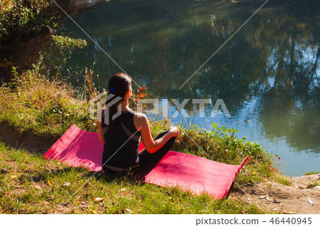 Back view of woman siting and relaxing near the water Back view of woman siting and relaxing near the water 46440945