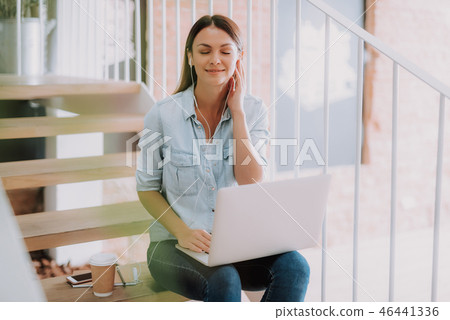 Charming young lady with white laptop listening music Charming young lady with white laptop listening music 46441336