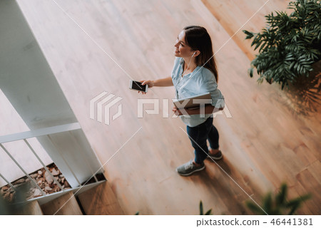 Cheerful young woman listening music on smartphone Cheerful young woman listening music on smartphone 46441381