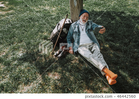 Senior man is sitting on grass in square 46442560