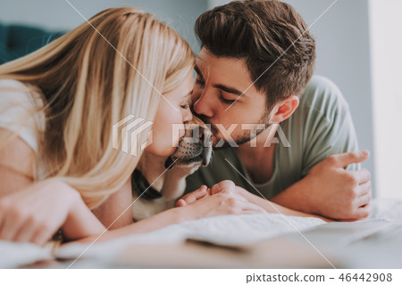 Young loving couple kissing their home pet Young loving couple kissing their home pet 46442908