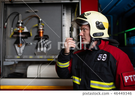 Image of male firefighter in helmet talking on walkie-talkie 46449346