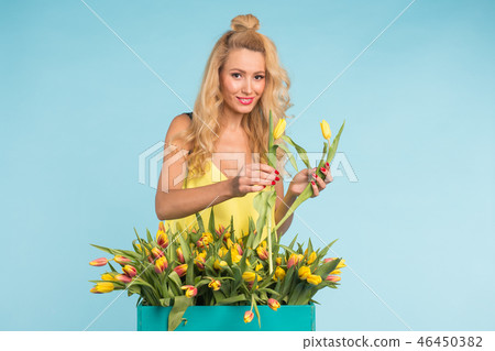 Charming blonde female florist sorts out tulips in the box, selects them for the future flower Charming blonde female florist sorts out tulips in the box, selects them for the future flower 46450382