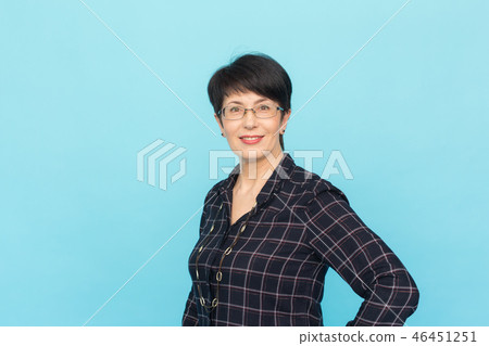 Fashion, people and style concept - Beautiful mid-aged woman wearing eye-glasses laughing on blue Fashion, people and style concept - Beautiful mid-aged woman wearing eye-glasses laughing on blue 46451251