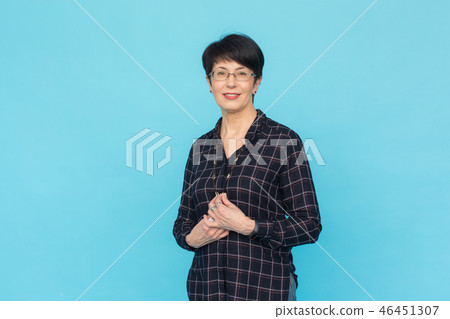 Mid-aged woman with short hair wearing glasses and shirt standing against blue background with copy Mid-aged woman with short hair wearing glasses and shirt standing against blue background with copy 46451307