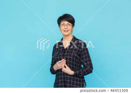 Mid-aged woman with short hair wearing glasses and shirt standing against blue background with copy Mid-aged woman with short hair wearing glasses and shirt standing against blue background with copy 46451309