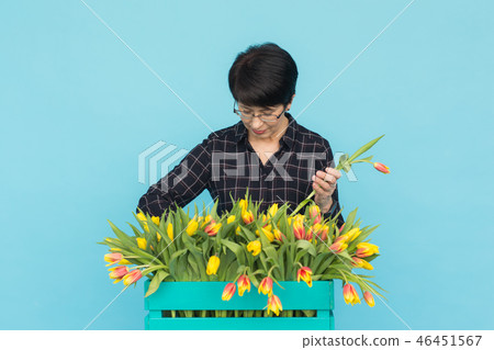 Charming brunette female florist sorts out tulips in the box, selects them for the future flower 46451567