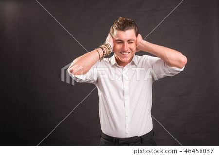 Handsome man covering his ears with both hands and looking at the camera on brown background. 46456037