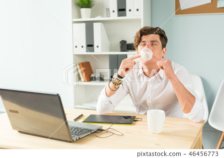 Business, fun and joke concept - young man blowing bubble of chewing gum in office Business, fun and joke concept - young man blowing bubble of chewing gum in office 46456773