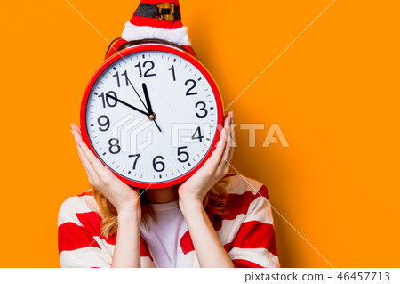 Woman hiding with big clock on on yellow background Woman hiding with big clock on on yellow background 46457713