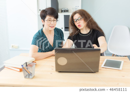 Business, technology and people concept - two women discuss a project watching in laptop 46458111