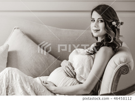 Young pregnant woman in white dress sitting Young pregnant woman in white dress sitting 46458112