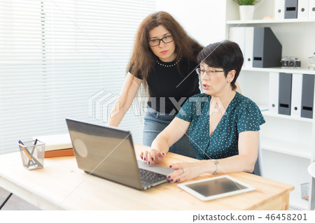 Technology, business and people concept - Young woman explaining something about laptop to her Technology, business and people concept - Young woman explaining something about laptop to her 46458201