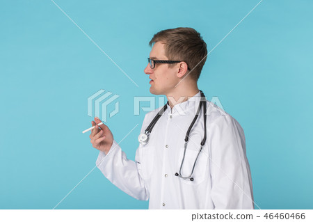 Stressed doctor smoking cigarettes on blue background 46460466