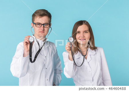 Two best smart professional smiling doctors workers in white coats showing stethoscope standing 46460488