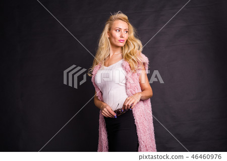 Fashion and beauty concept - portrait of blond model in pink cardigan posing over dark background Fashion and beauty concept - portrait of blond model in pink cardigan posing over dark background 46460976