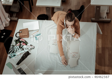 Tall handsome designer in a brown garment looking thoughtful Tall handsome designer in a brown garment looking thoughtful 46462387