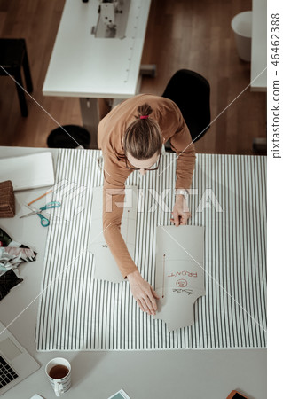 Young fair-haired designer in a brown garment looking busy at the workshop Young fair-haired designer in a brown garment looking busy at the workshop 46462388