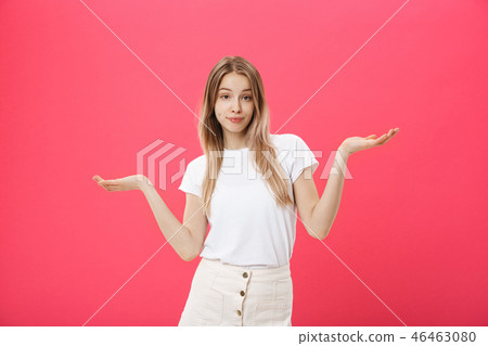 Emotional beautiful and positive young woman with boring face looks forward, spreading her hands to 46463080