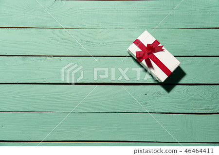 White gift box with red bow on green wooden planks White gift box with red bow on green wooden planks 46464411