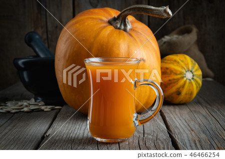 Glass cup of pumpkin juice and pumpkins on table. Glass cup of pumpkin juice and pumpkins on table. 46466254