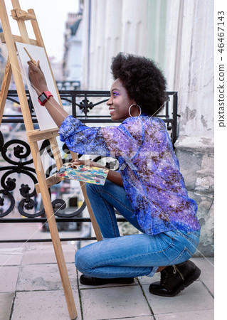 Beaming artist wearing jeans and blue blouse painting 46467143