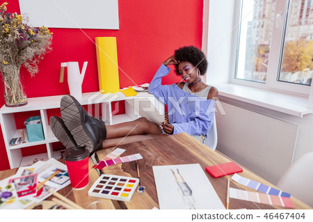 Fashion designer putting her legs on the table while looking at sketches 46467404