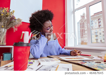 Beaming artist drinking coffee and painting some sketches 46467645