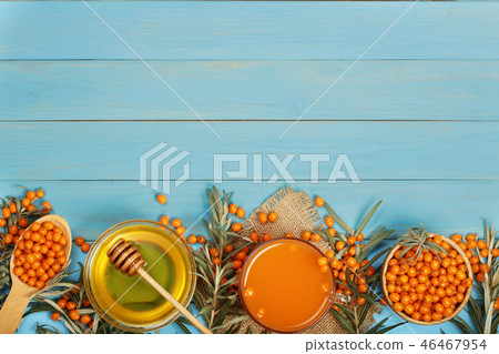 Sea buckthorn juice or tea with honey on a blue wooden background with copy space for your text. Top 46467954