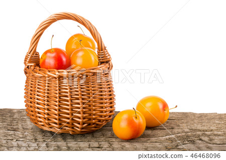 yellow plums with leaf in a wicker basket on wooden table with white background yellow plums with leaf in a wicker basket on wooden table with white background 46468096