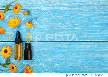 aromatherapy essential oil with marigold flowers on blue background with copy space for your text aromatherapy essential oil with marigold flowers on blue background with copy space for your text 46468358