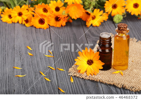 aromatherapy essential oil with fresh marigold flowers on old wooden background. Calendula oil 46468372