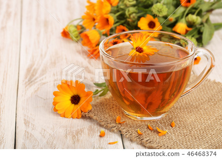 Calendula tea with fresh flowers on white wooden background Calendula tea with fresh flowers on white wooden background 46468374