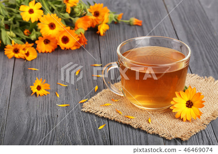 Calendula tea with fresh flowers on black wooden background Calendula tea with fresh flowers on black wooden background 46469074