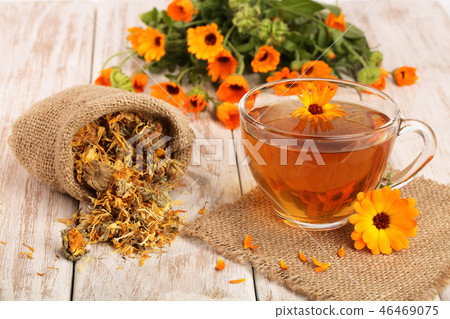 Calendula tea with fresh and dried flowers on white wooden background Calendula tea with fresh and dried flowers on white wooden background 46469075