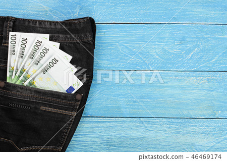 one hundred euro banknotes in a jeans pocket on blue wooden background with copy space for your text one hundred euro banknotes in a jeans pocket on blue wooden background with copy space for your text 46469174