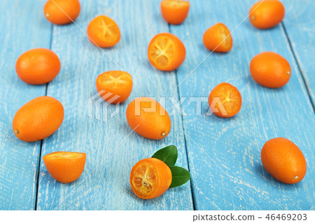 Cumquat or kumquat with half on blue wooden background Cumquat or kumquat with half on blue wooden background 46469203