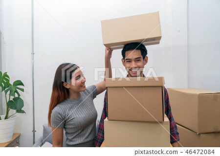 Asian young couple carrying big cardboard box for moving in new house, Helping relocate and joshing together, Moving and House Hunting concept Asian young couple carrying big cardboard box for moving in new house, Helping relocate and joshing together, Moving and House Hunting concept 46472084