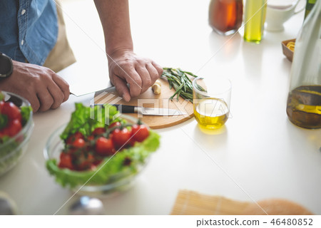 Man crushing garlic with the flat of a knife on cutting board Man crushing garlic with the flat of a knife on cutting board 46480852