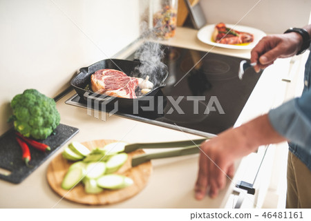 Piece of meat with steam frying on stovetop while man holding fork Piece of meat with steam frying on stovetop while man holding fork 46481161