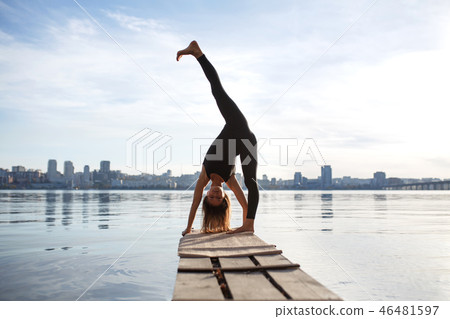 Young woman practicing yoga exercise at quiet pier Young woman practicing yoga exercise at quiet pier 46481597
